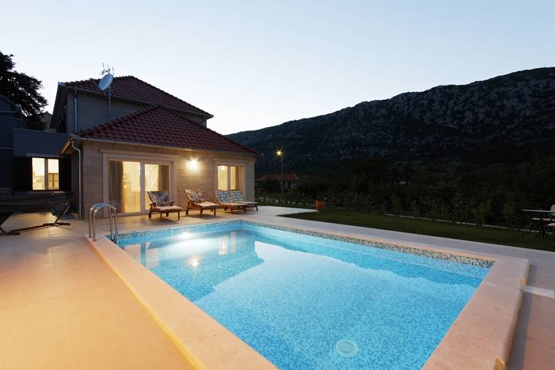 Illuminated Villa Zupa and its yard with the swimming pool in the evening