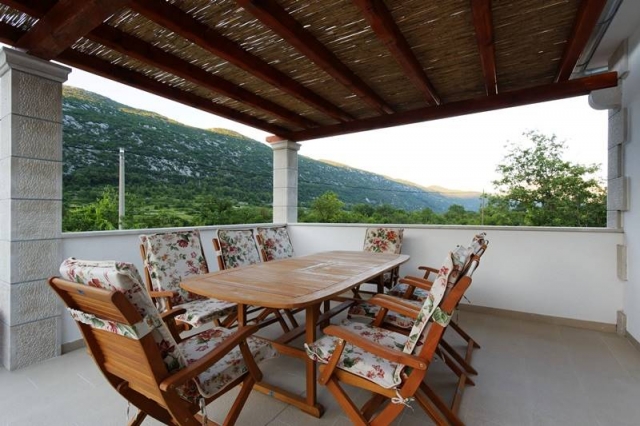 Covered terrace on the upper floor with the dining table and mountain view