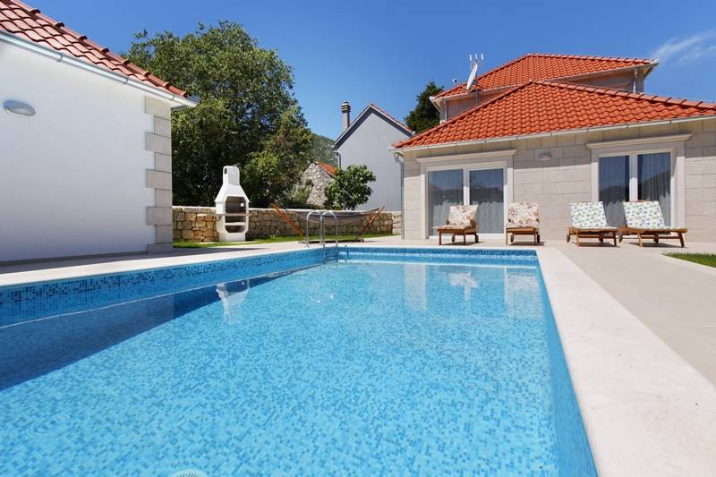 Swimming pool with sunbeds and open fireplace in the yard of the Villa Zupa